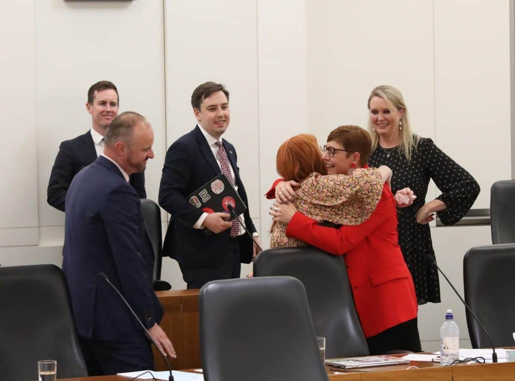 Photo from Riotact shows Human Rights Minister Tara Cheyne’s (centre) hugging Health Minister Rachel Stephen-Smith